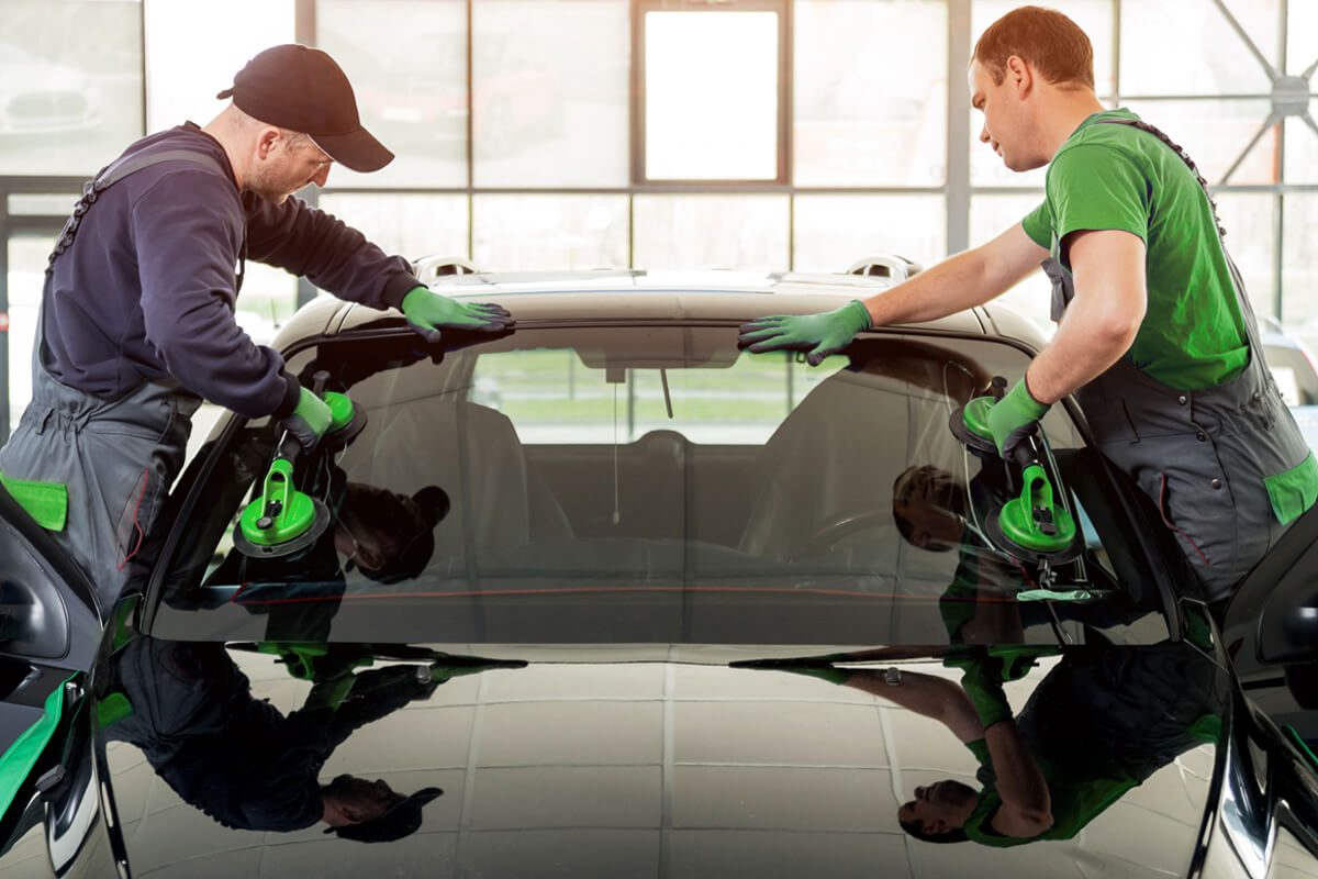 Zwei Mitarbeiter tauschen die Autoscheibe aus
